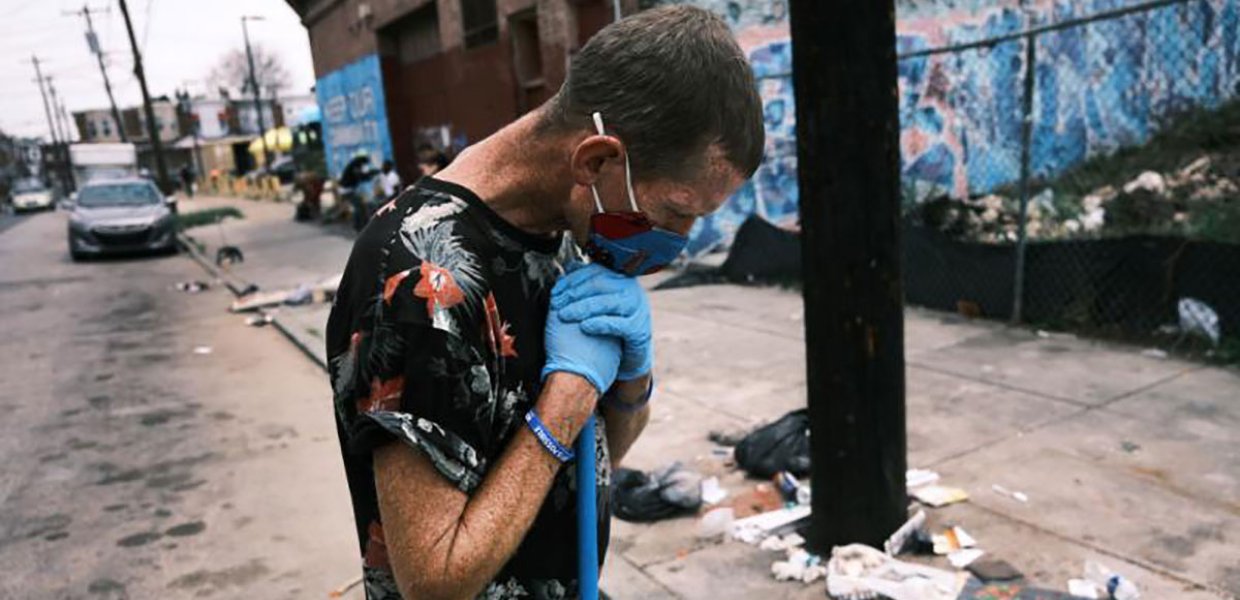 Photo of a person wearing medical gloves and a mask in a street