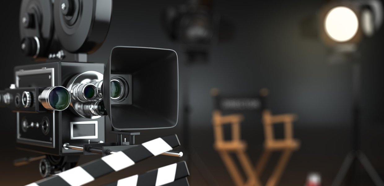 A film camera points off screen. A director's chair and a key light is in the background.