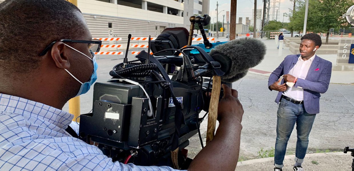 Photo of a person recording another person with a media camera on the street