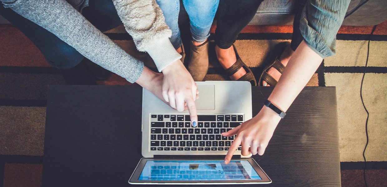 Three women around a laptop. 