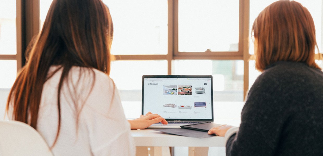 Photo of two women talking in front of a computer