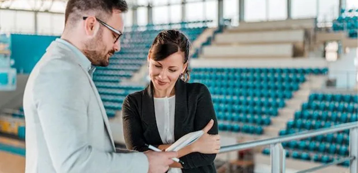 Two people looking at clipboard in gymnasium.