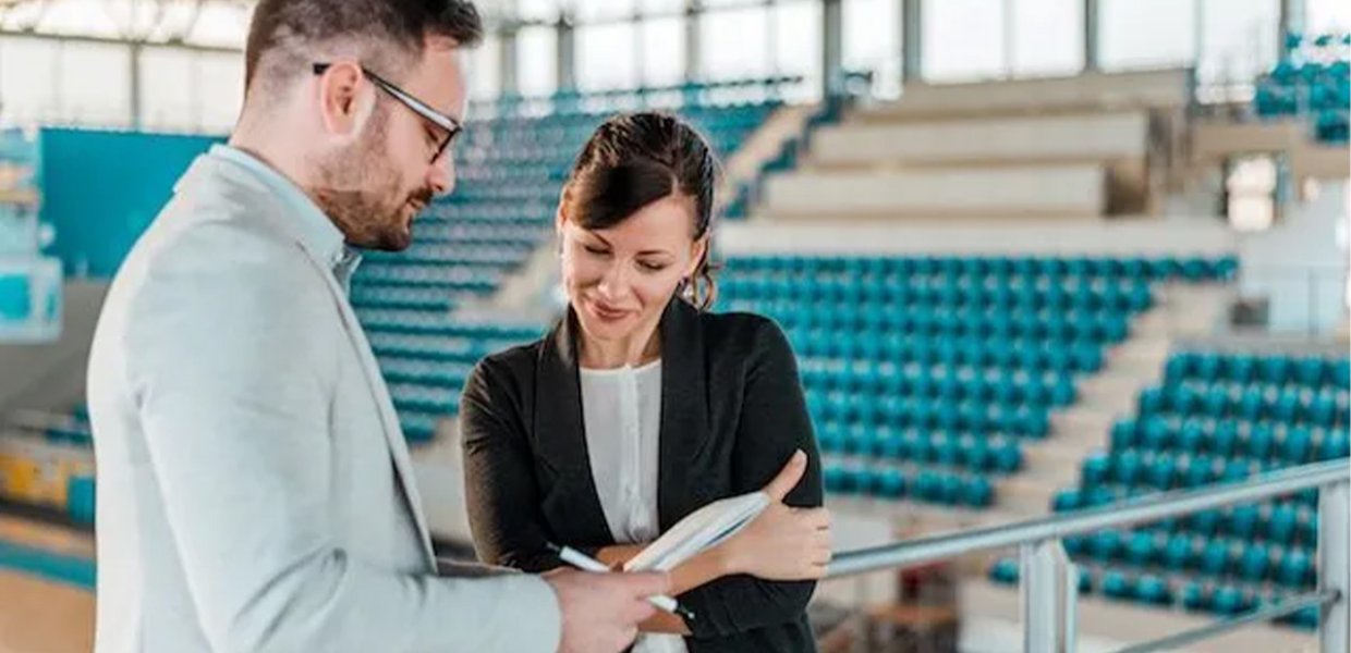 Two people looking at clipboard in gymnasium. 