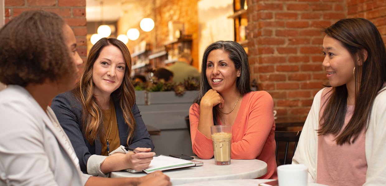 Four women sitting at table.