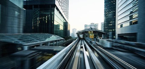 A tram moving quickly on a track in a futuristic city