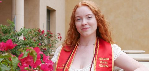 women with red hair wearing graduation stoll poses by flowers