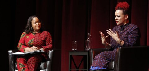 two Black women in conversation seated on stage