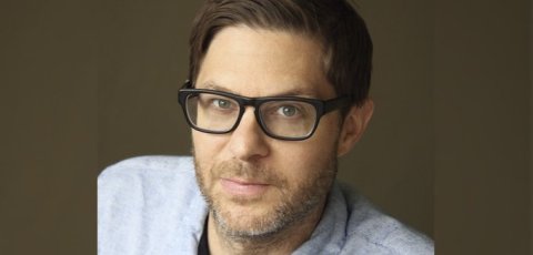 portrait of middle aged man wearing black rimmed glasses and soft grey shirt