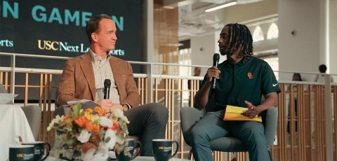 In the Wallis Annenberg Hall Forum, Peyton Manning, left, engages with student Elijah Patterson, right, who holds a mic and asks a question.