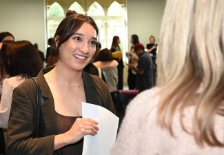 Student speaking to another person at a Career Fair, resume in hand.