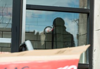 A photo of a window with a reflection of a person with a megaphone.