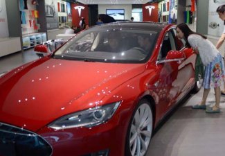 Photo of a Tesla vehicle with people inside the car and another couple looking into it