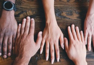 Photo of five different hands on a table