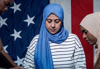 Women, wearing headscarfs, making American flags