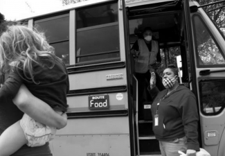 Photo of a child being held by an adult in front of a bus