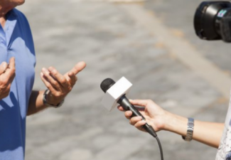 Image of person interviewing another person with camera and microphone