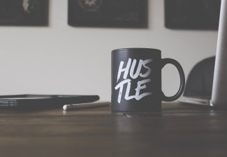 Photo of a mug that says "hustle" on a desk