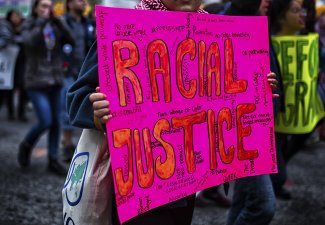 Photo of person holding a sign that says "racial justice"