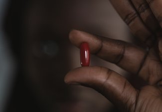 A person holding a red pill