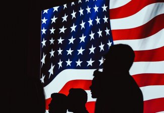 Photo of the silhouettes of people in front of the American flag