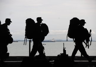 Silhouette of army men walking in single file