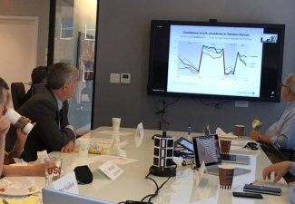 Men in a conference room looking at a chart on the television