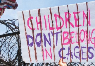 Photo of a sign that reads "children don't belong in cages"