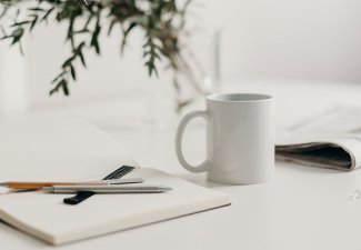 Photo of a coffee mug and notebooks on a desk