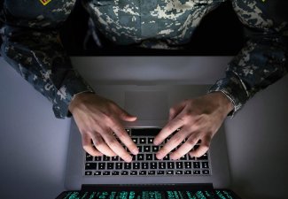 Photo of a person in a U.S. Army uniform typing on a laptop