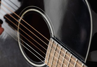 Photo of a black guitar being strummed