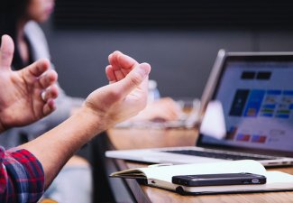 Hands gesticulating in front of a laptop on a table