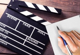 Photo of a person writing on a notepad next to a clapperboard