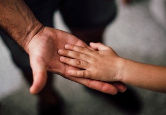 Photo of a person holding a child's hand