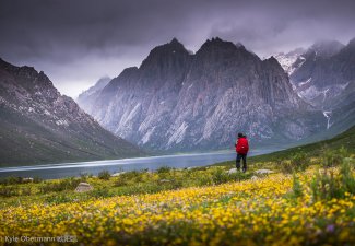 Photo of a mountainous landscape and a person standing in the right of the photo