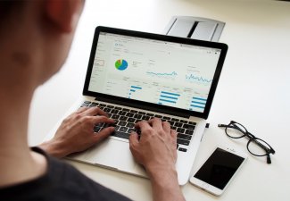 Photo of a person working on bars and graphs on a computer