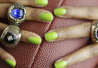 Photo of a person with green fingernails holding a football