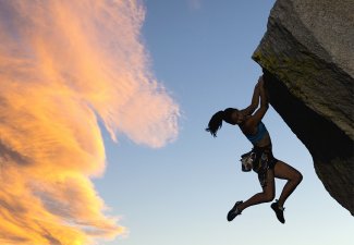 Photo of a person holding onto the side of a cliff