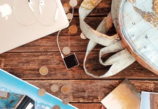 Photo of a table with a laptop, headphones, a backpack, and a map