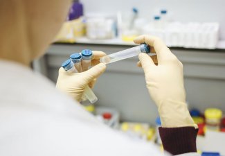 Photo of a person holding four vaccine vials in their hands