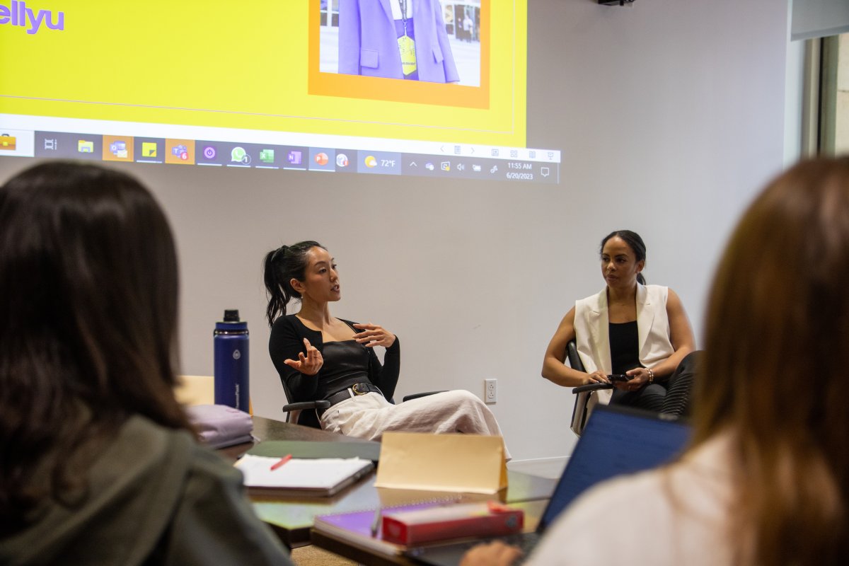 Two women in conversation while students listen