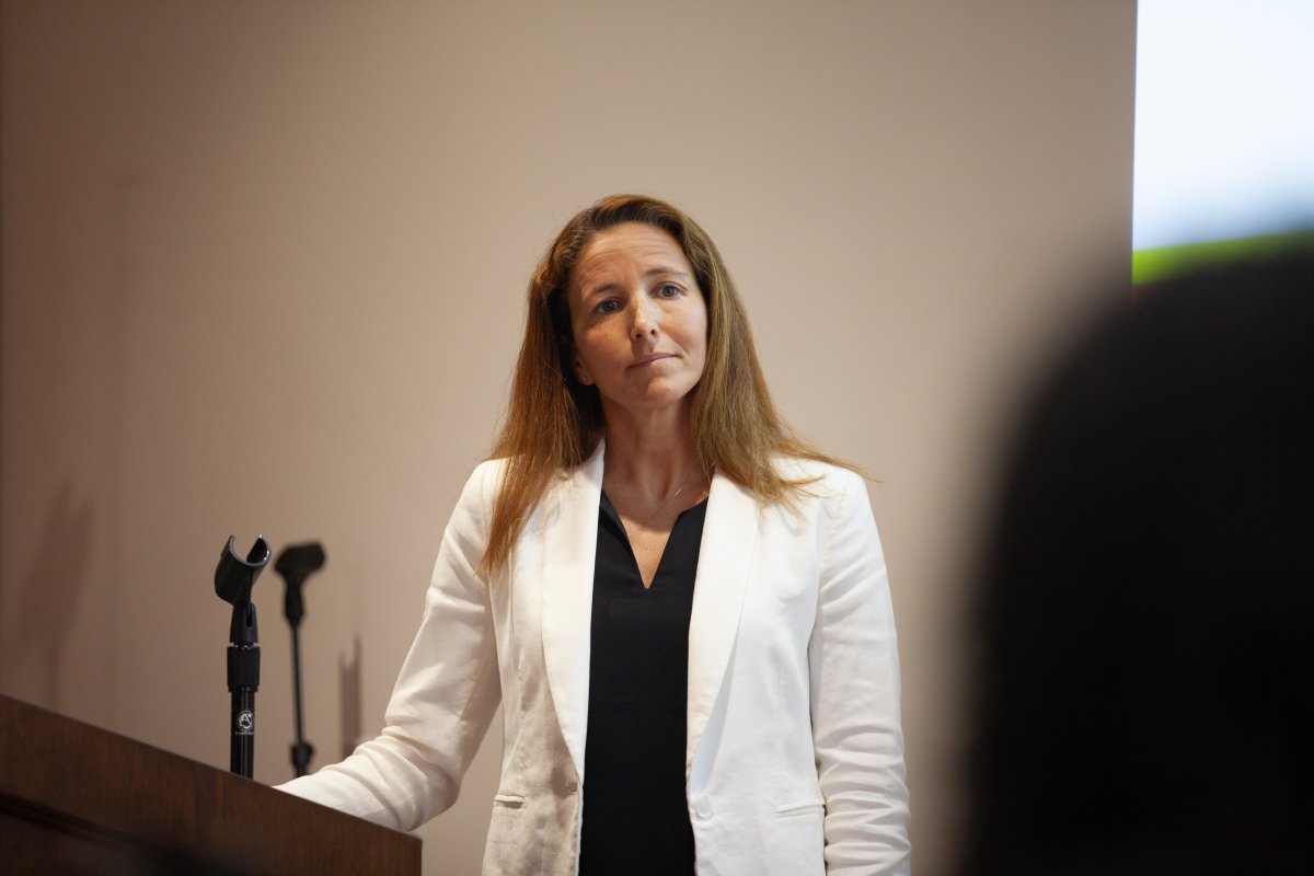 women in white blazer stands at podium