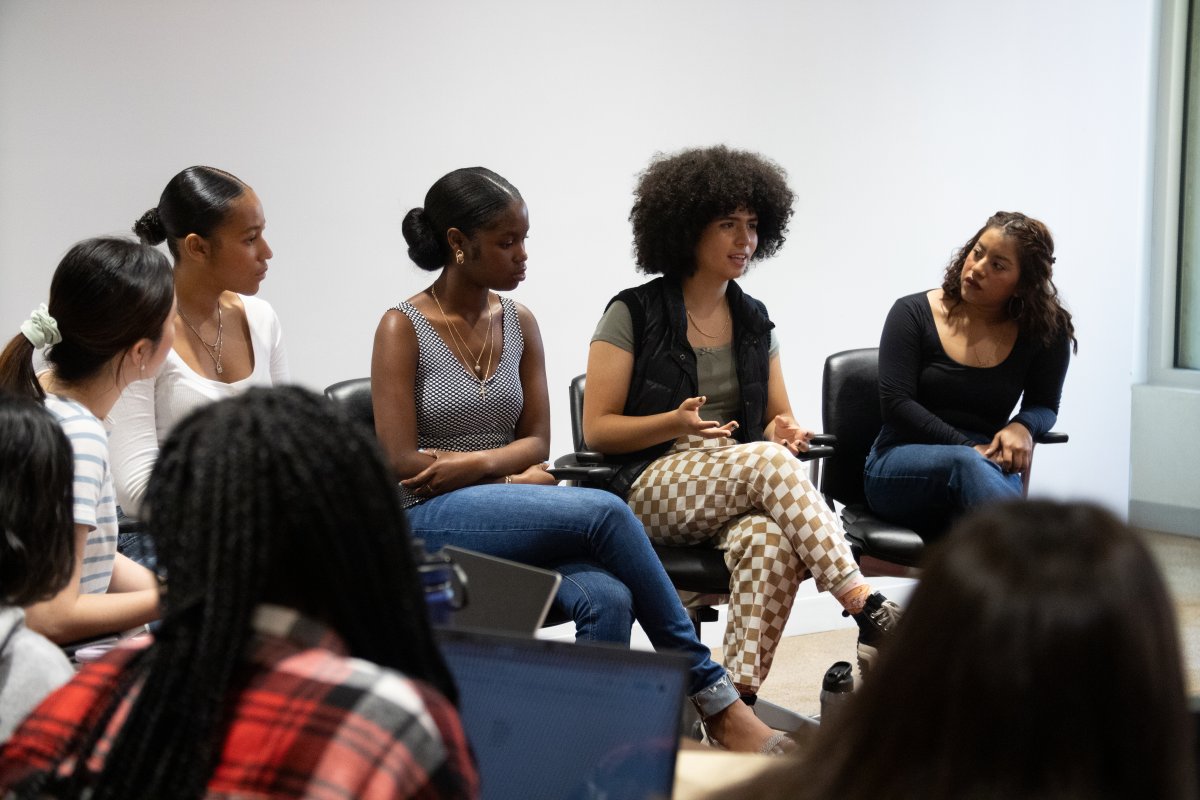 five college aged women sit in chairs in front of audiance