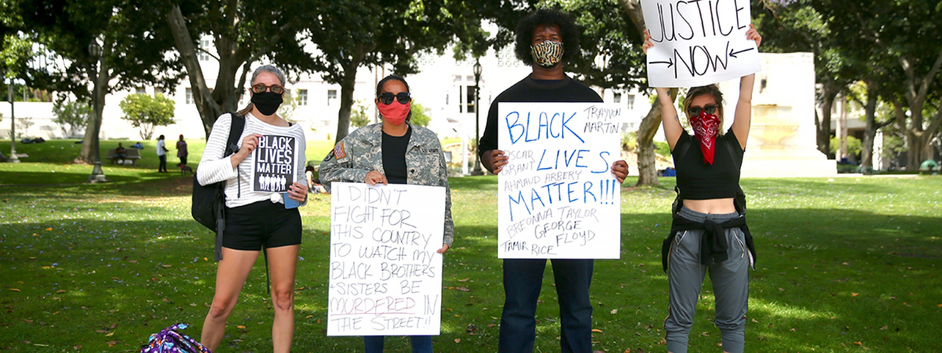 Photo of four people holding signs for Black Lives Matter and racial justice