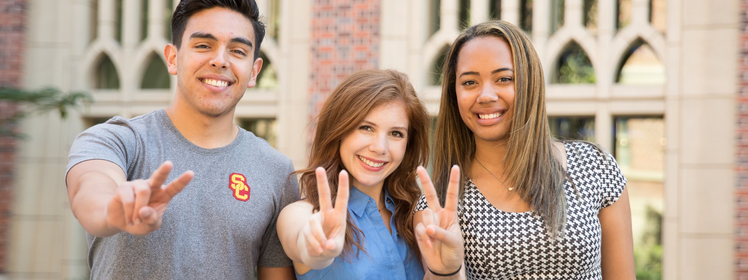 Three students holding up a peace sign in front of ANN