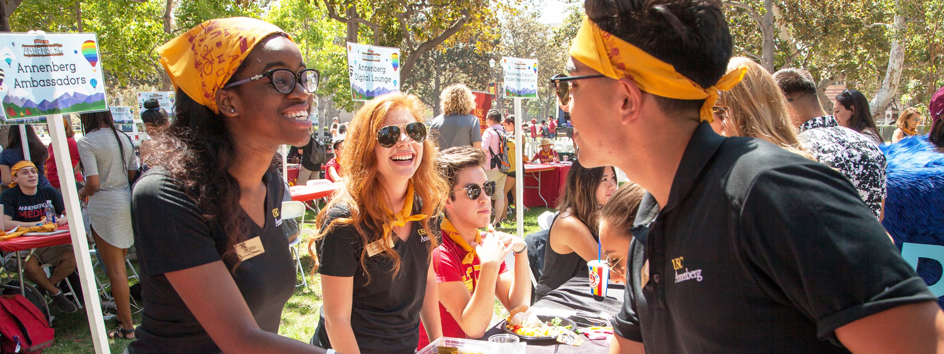Three Annenberg ambassadors shaking hands at an outdoor table set up