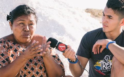 middle aged Hispanic woman is speaking while male Hispanic college student holds microphone for interview.