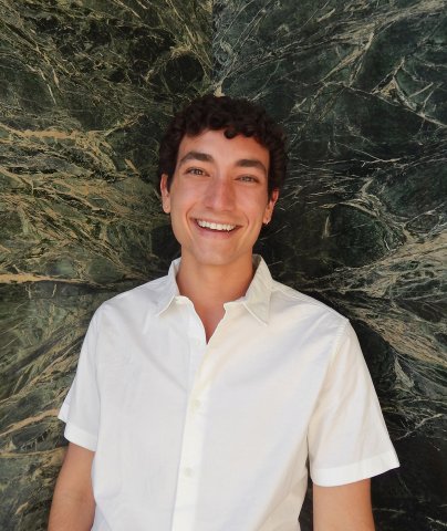 USC Annenberg student Charlie Siegel stands in front of a green marble wall with a white shirt.