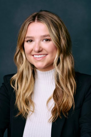 Tess Patton wears white turtle neck and black blazor and smiles for camera