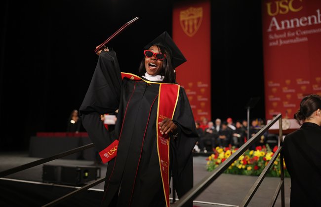 Woman in the sunglasses receiving her diploma at commencement 2025.