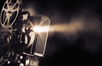 An old fashioned movie camera shines a bright light in a dark background.